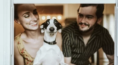 Dog standing with two owners at home for a guide to choosing puzzle toys for home-alone dogs